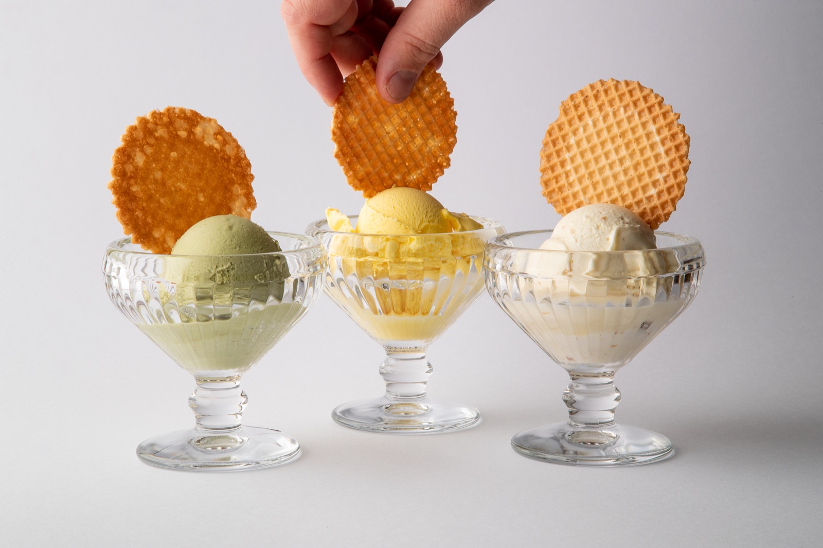 Drei Schlotzeria-Eisbecher: Pistazie, Mango und Vanille, jeweils mit Waffel